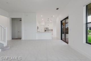 Unfurnished living room featuring light tile patterned floors and stairs