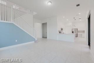 Unfurnished living room featuring stairs and light tile patterned floors