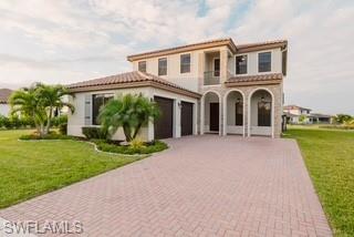 Mediterranean / spanish-style home featuring a front yard, a tile roof, decorative driveway, and stucco siding