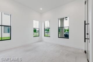 Empty room featuring light carpet, healthy amount of natural light, and recessed lighting