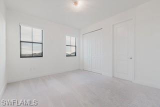 Unfurnished bedroom with light colored carpet and a closet