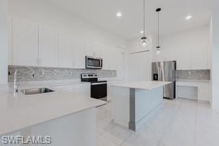 Kitchen with a breakfast bar, white cabinets, hanging light fixtures, appliances with stainless steel finishes, and recessed lighting