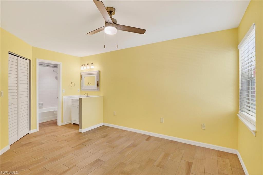 Unfurnished bedroom with light wood-style flooring, ensuite bathroom, a ceiling fan, and a closet