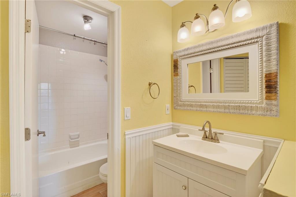 Full bath with wainscoting, vanity, and shower / bathtub combination