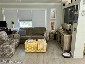 Living area featuring ornamental molding and light wood-style flooring