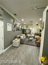 Living area with wood finished floors and ornamental molding