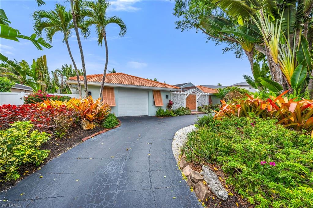 View of front of home featuring a tiled roof, stucco siding, driveway, and a garage