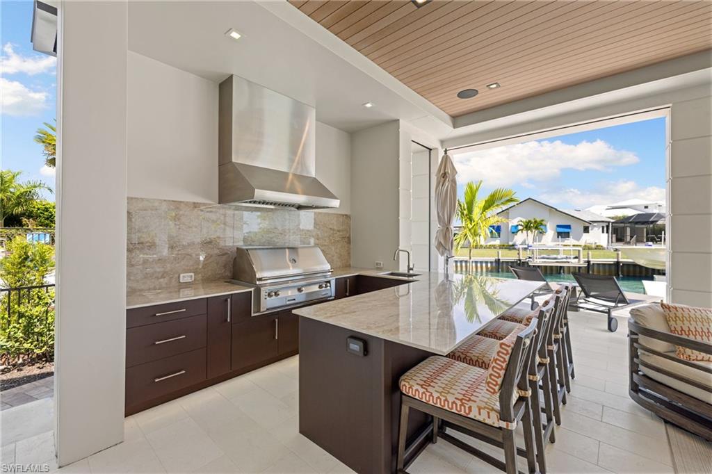 Kitchen featuring dark wood finish cabinets, light stone countertops, a kitchen bar, a peninsula, and wooden ceiling