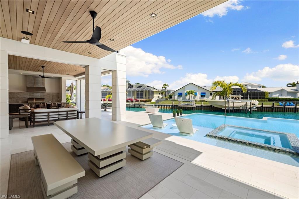 View of patio featuring a ceiling fan, an outdoor living / dining area, a residential view, and a pool with connected hot tub