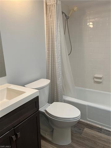 Bathroom with vanity, dark wood-type flooring, and shower / bath combo with shower curtain