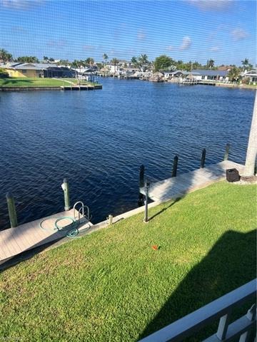 Dock area featuring a water view, a lawn, and a residential view