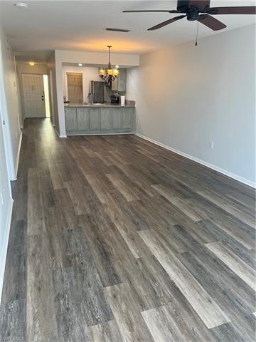 Unfurnished living room with hanging lights, dark wood-style flooring, and ceiling fan
