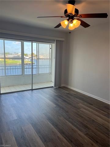Spare room featuring a ceiling fan, dark wood finished floors, and a water view