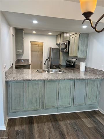 Kitchen featuring stainless steel appliances, light stone countertops, dark wood-type flooring, recessed lighting, and a peninsula