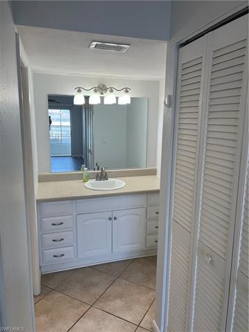 Bathroom featuring a closet, vanity, and light tile patterned floors