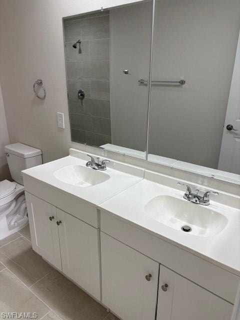 Bathroom featuring double vanity, tiled shower, and light tile patterned flooring