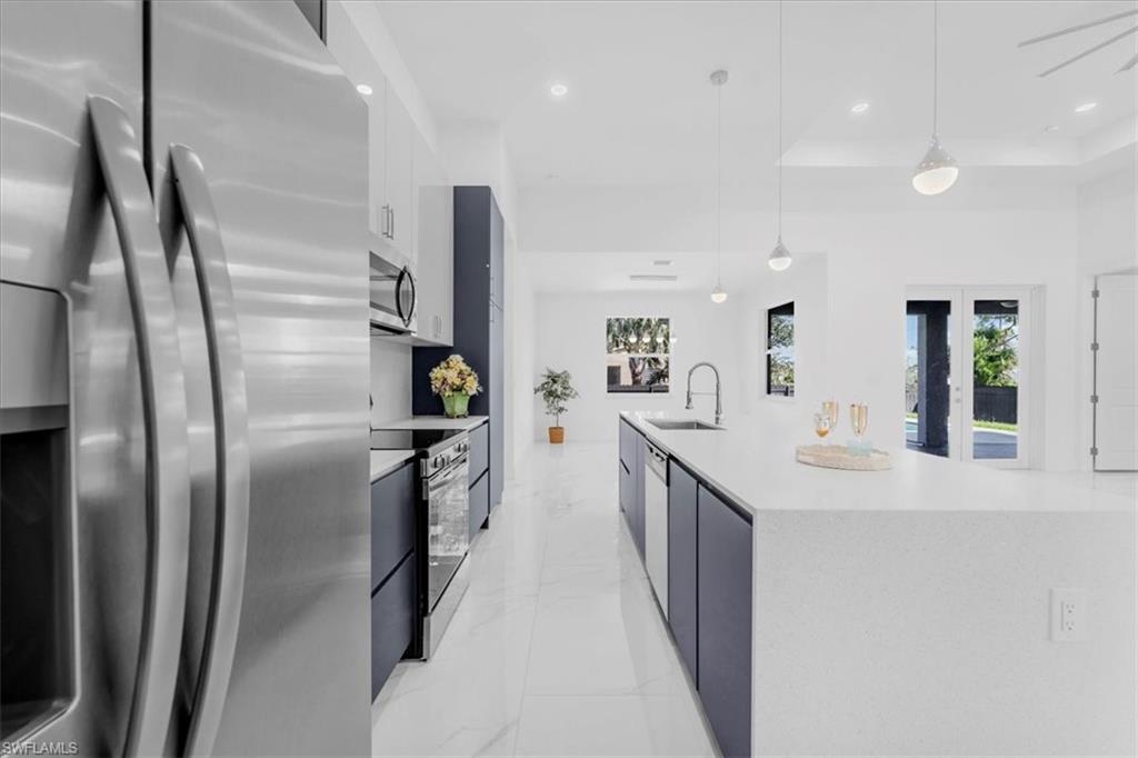 Kitchen with stainless steel appliances, modern cabinets, a spacious island, white cabinetry, and a raised ceiling