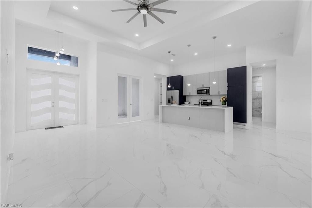 Unfurnished living room with a high ceiling, recessed lighting, a ceiling fan, and french doors