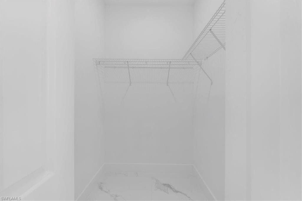 Walk in closet featuring light marble finish floors
