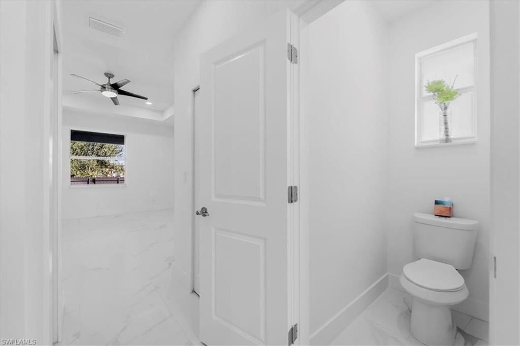 Bathroom with light marble finish flooring, a ceiling fan, and recessed lighting
