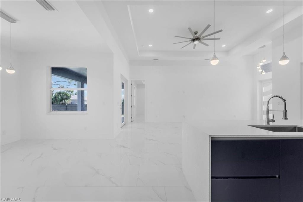 Kitchen featuring decorative light fixtures, light stone counters, ceiling fan, modern cabinets, and open floor plan