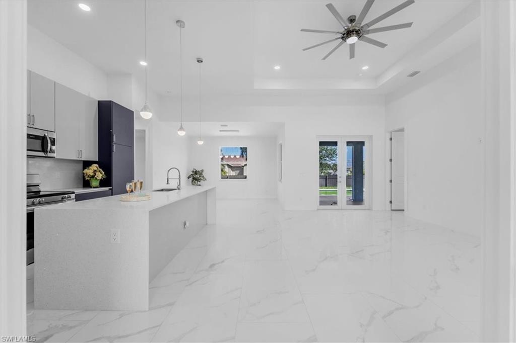 Kitchen featuring hanging light fixtures, stainless steel appliances, light stone counters, modern cabinets, and open floor plan