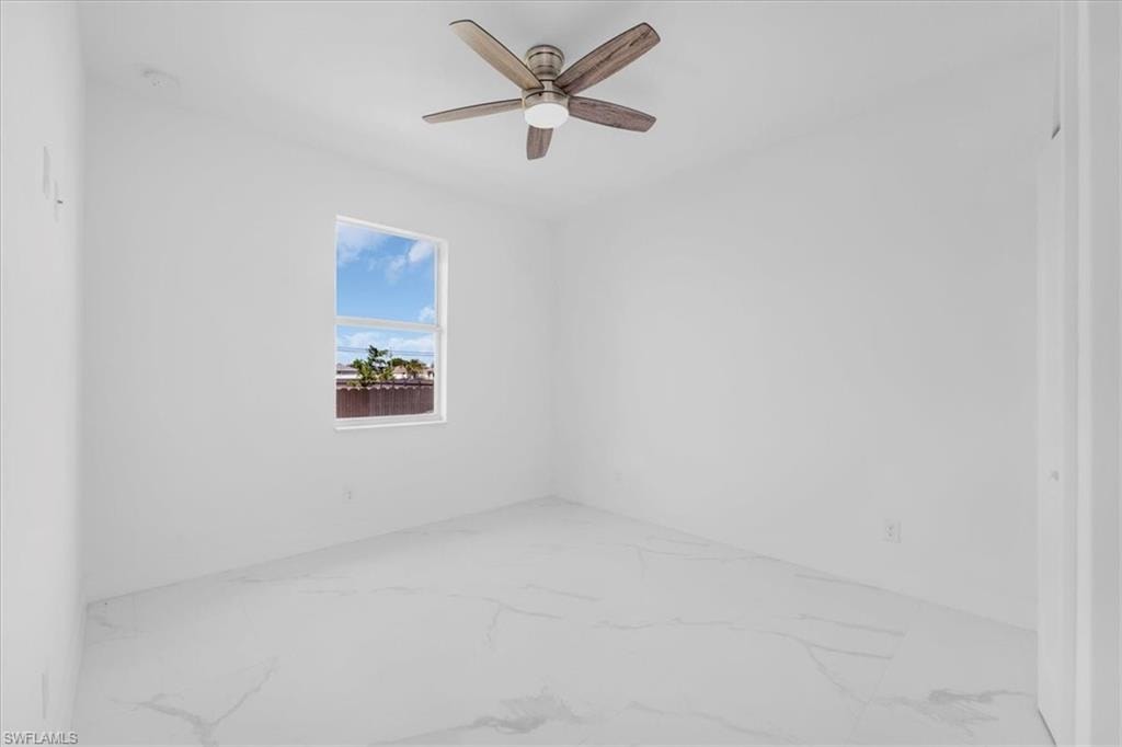 Empty room with a ceiling fan and light marble finish flooring