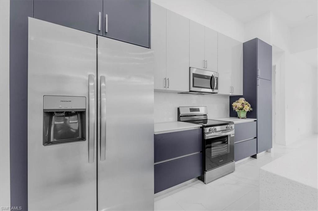 Dual tone kitchen featuring stainless steel appliances, modern cabinets, dual tone cabinetry, and light marble finish flooring