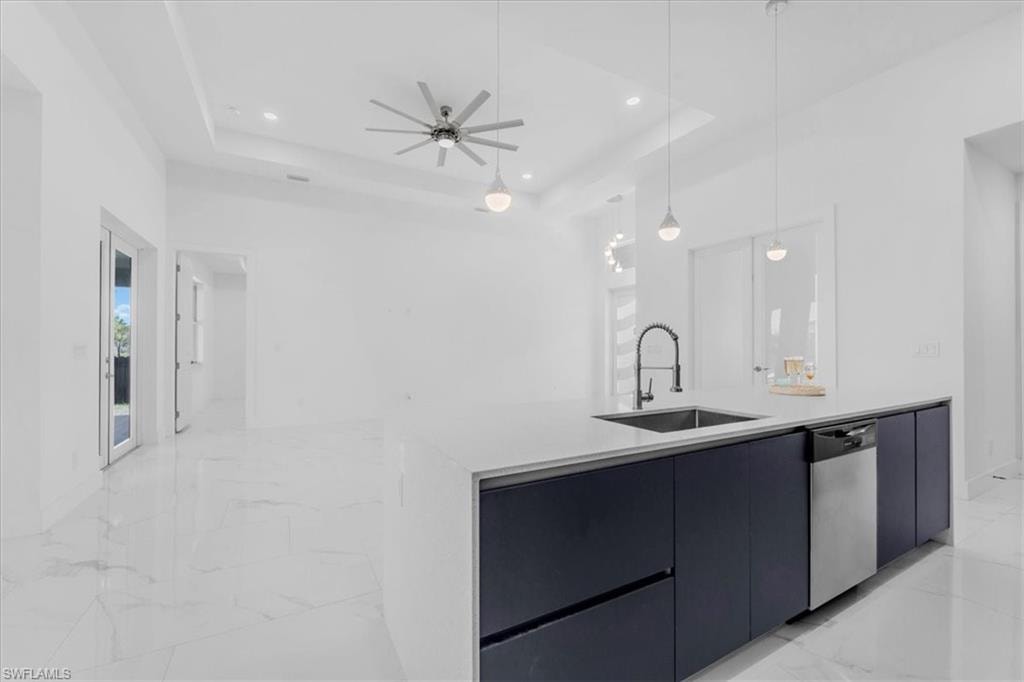 Kitchen with modern cabinets, an island with sink, light stone countertops, stainless steel dishwasher, and light marble finish floors