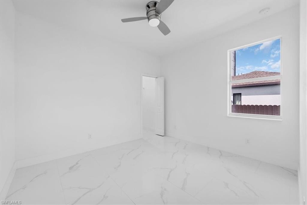 Empty room featuring ceiling fan and light marble finish flooring
