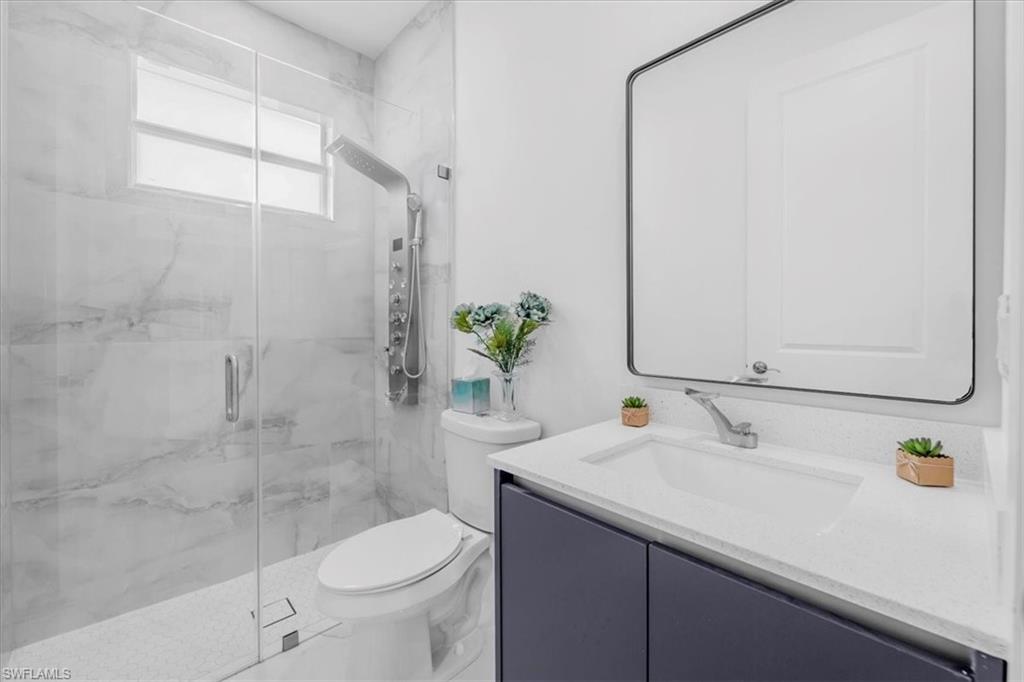 Bathroom featuring vanity and a marble finish shower