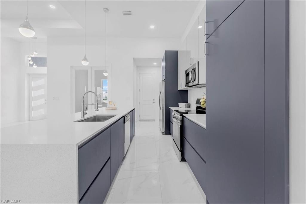Kitchen with modern cabinets, stainless steel appliances, light stone countertops, and light marble finish floors