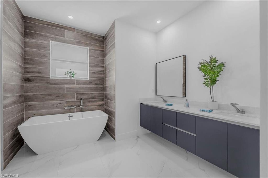 Full bath with double vanity, a freestanding bath, and recessed lighting