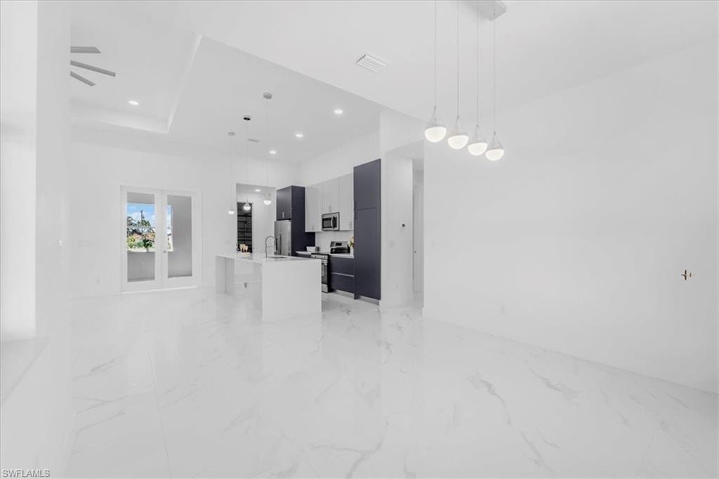 Kitchen with a center island with sink, modern cabinets, pendant lighting, open floor plan, and stainless steel appliances