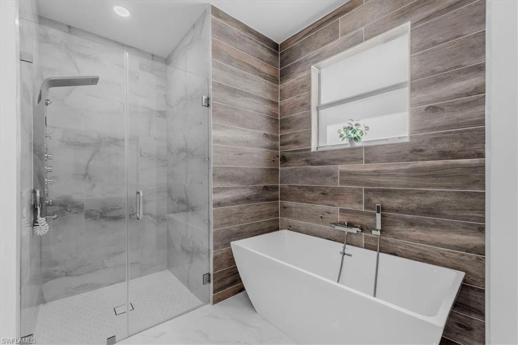 Bathroom featuring a marble finish shower and a freestanding bath