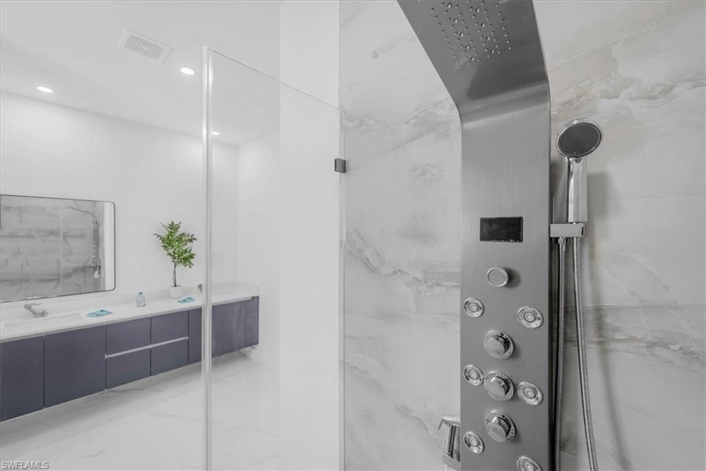 Full bathroom featuring vanity, a marble finish shower, and recessed lighting