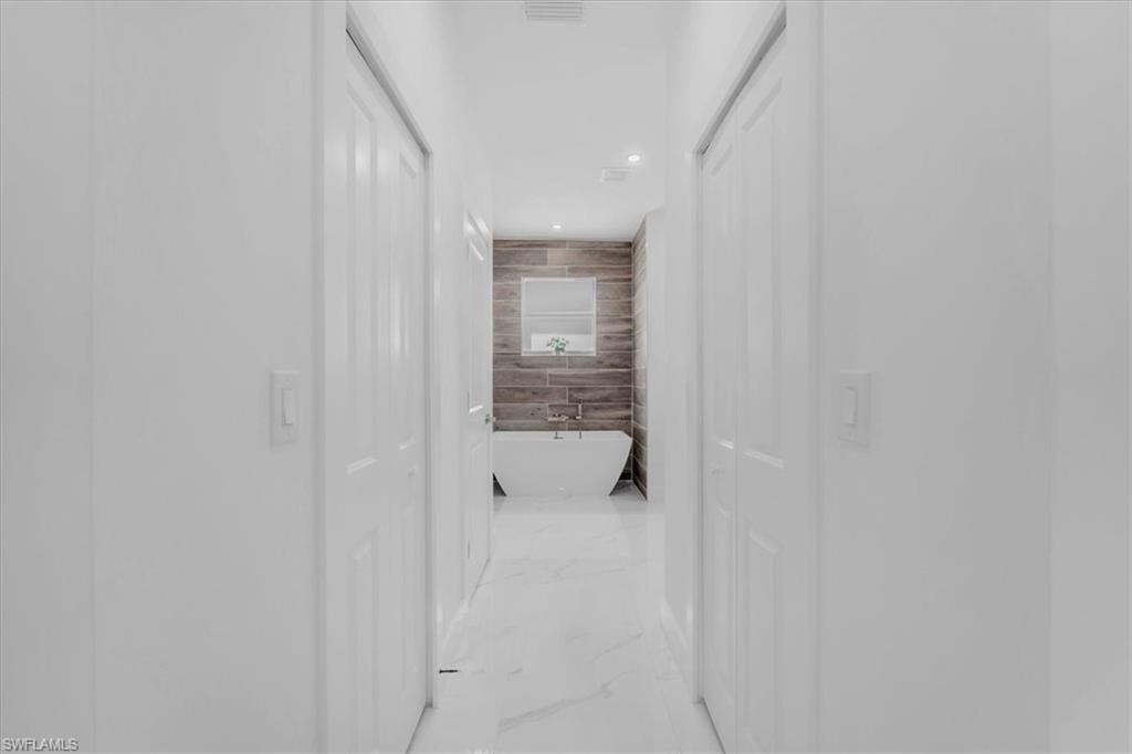 Hall featuring recessed lighting and tile walls