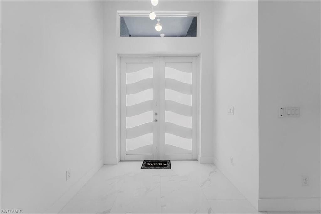 Foyer featuring light marble finish flooring and french doors