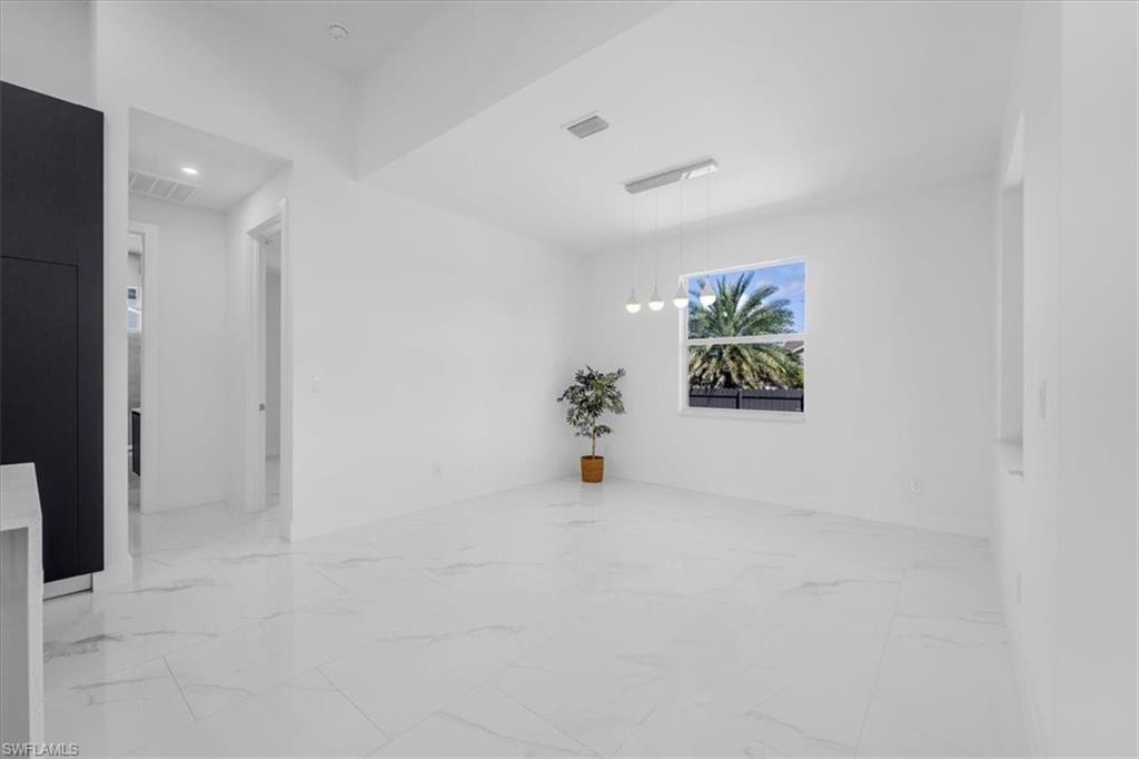 Unfurnished room featuring hanging lights and light marble finish flooring