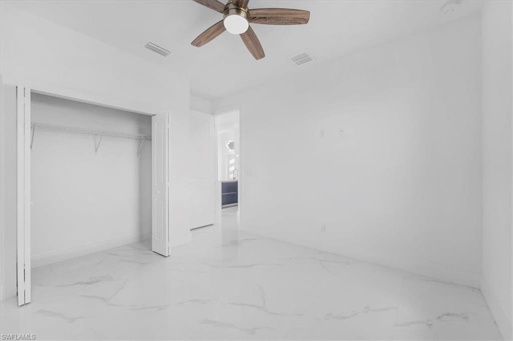 Unfurnished bedroom with ceiling fan, a closet, and light marble finish floors