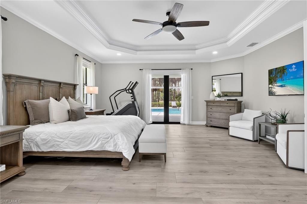 Bedroom featuring light wood-style flooring, crown molding, ceiling fan, access to outside, and a tray ceiling