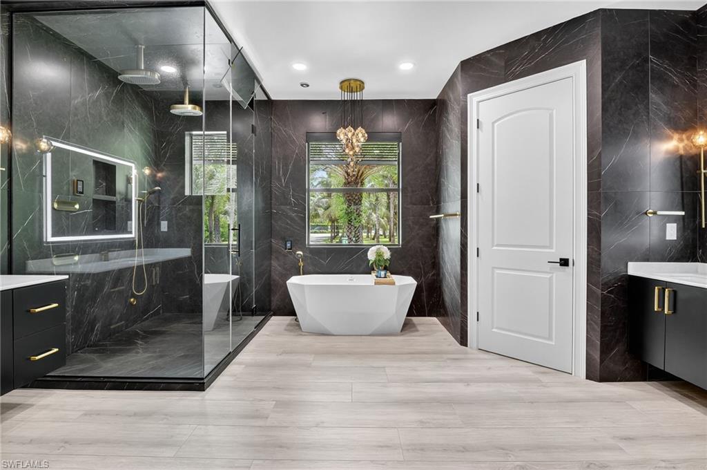 Bathroom with vanity, tile walls, a soaking tub, a marble finish shower, and recessed lighting