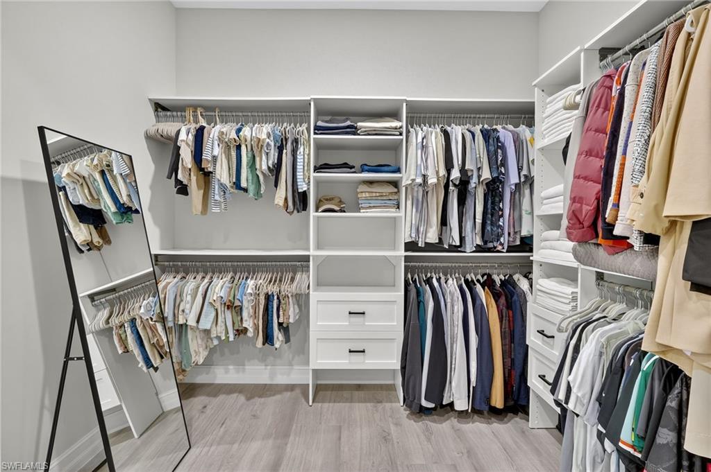 Walk in closet with light wood finished floors