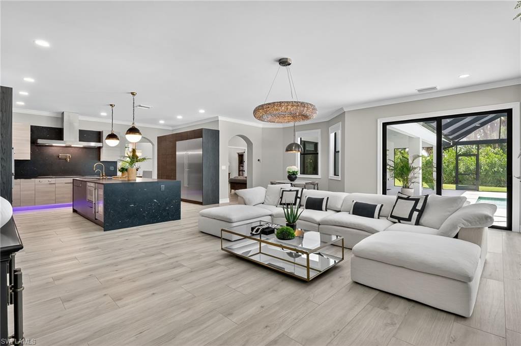 Living area with recessed lighting, ornamental molding, light wood-type flooring, and arched walkways