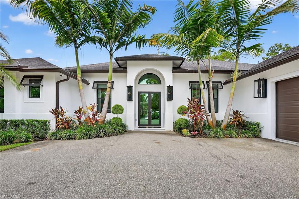 View of exterior entry with stucco siding, an attached garage, and asphalt driveway