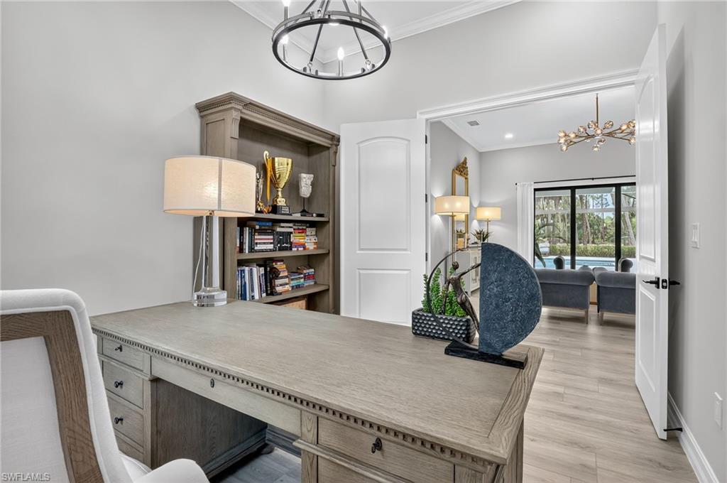 Office with suspended lighting, ornamental molding, and light wood finished floors