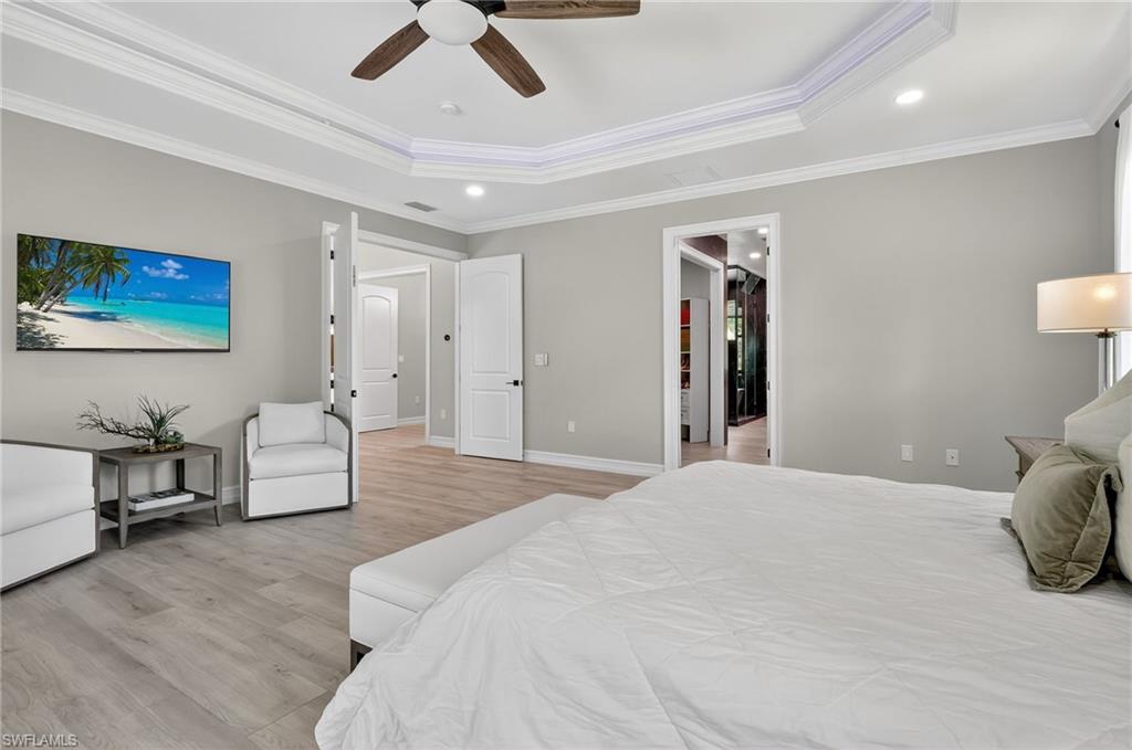 Bedroom featuring light wood finished floors, ornamental molding, a ceiling fan, a raised ceiling, and recessed lighting