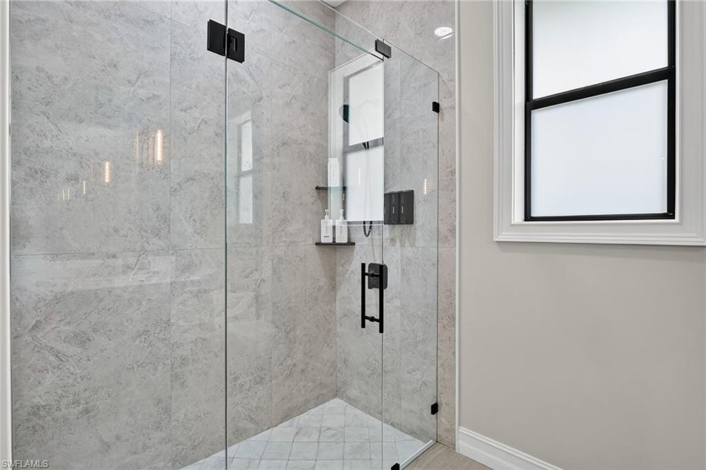 Bathroom featuring a marble finish shower and baseboards