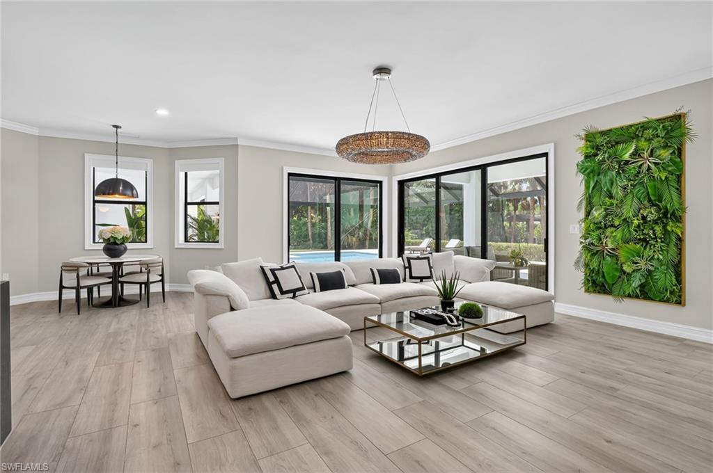 Living area with light wood-style floors, crown molding, plenty of natural light, and recessed lighting