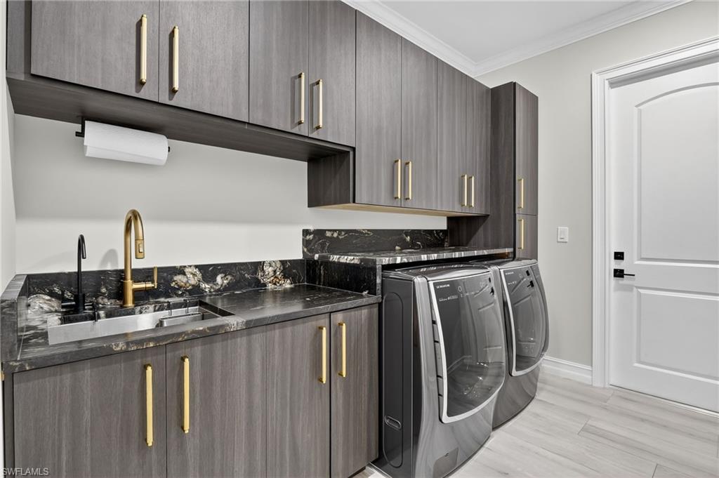 Laundry room featuring cabinet space, ornamental molding, independent washer and dryer, and light wood-type flooring